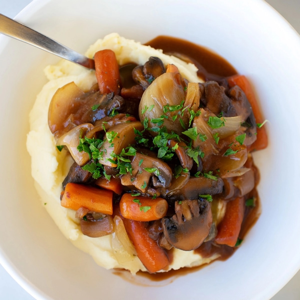 Close-up shows the warmly colored, comforting Rustic Mushroom and Shallot Stew over root mash.