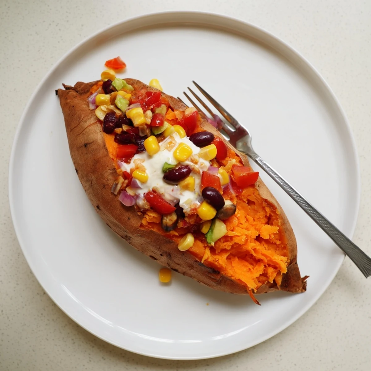 A close-up of a delightful Loaded Baked Sweet Potato, showing off the colorful toppings and dollops of yogurt.