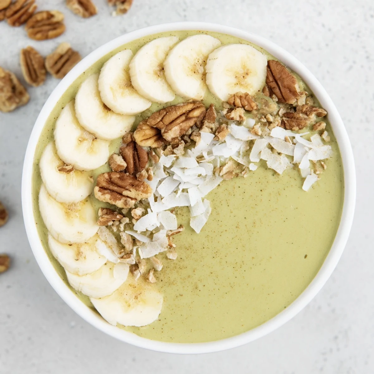Creamy High-Protein Eggnog Matcha Overnight Oats with banana slices and toasted coconut, ready to eat.