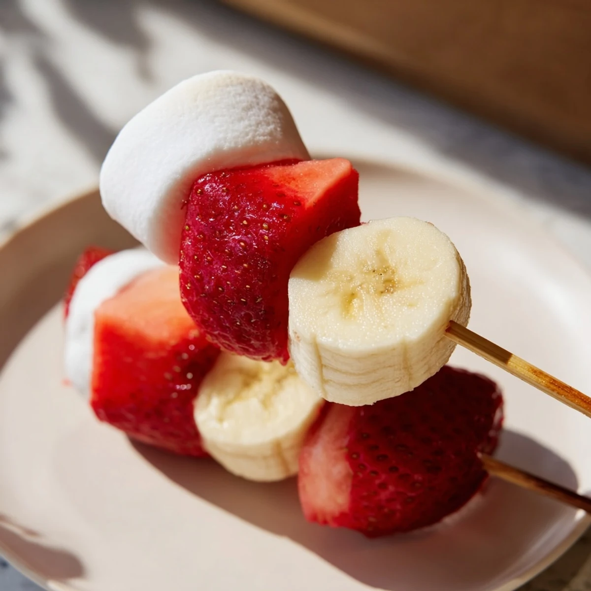 Sweet Strawberry Banana Santa Sticks recipe shows colorful fruit and marshmallows assembled for a snack.