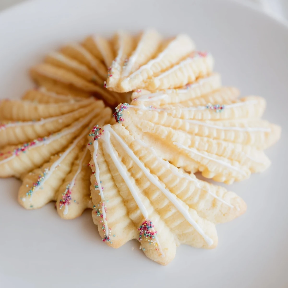 Golden-edged Spritz Cookies layered in fan shapes, ready to enjoy with a warm cup of coffee.