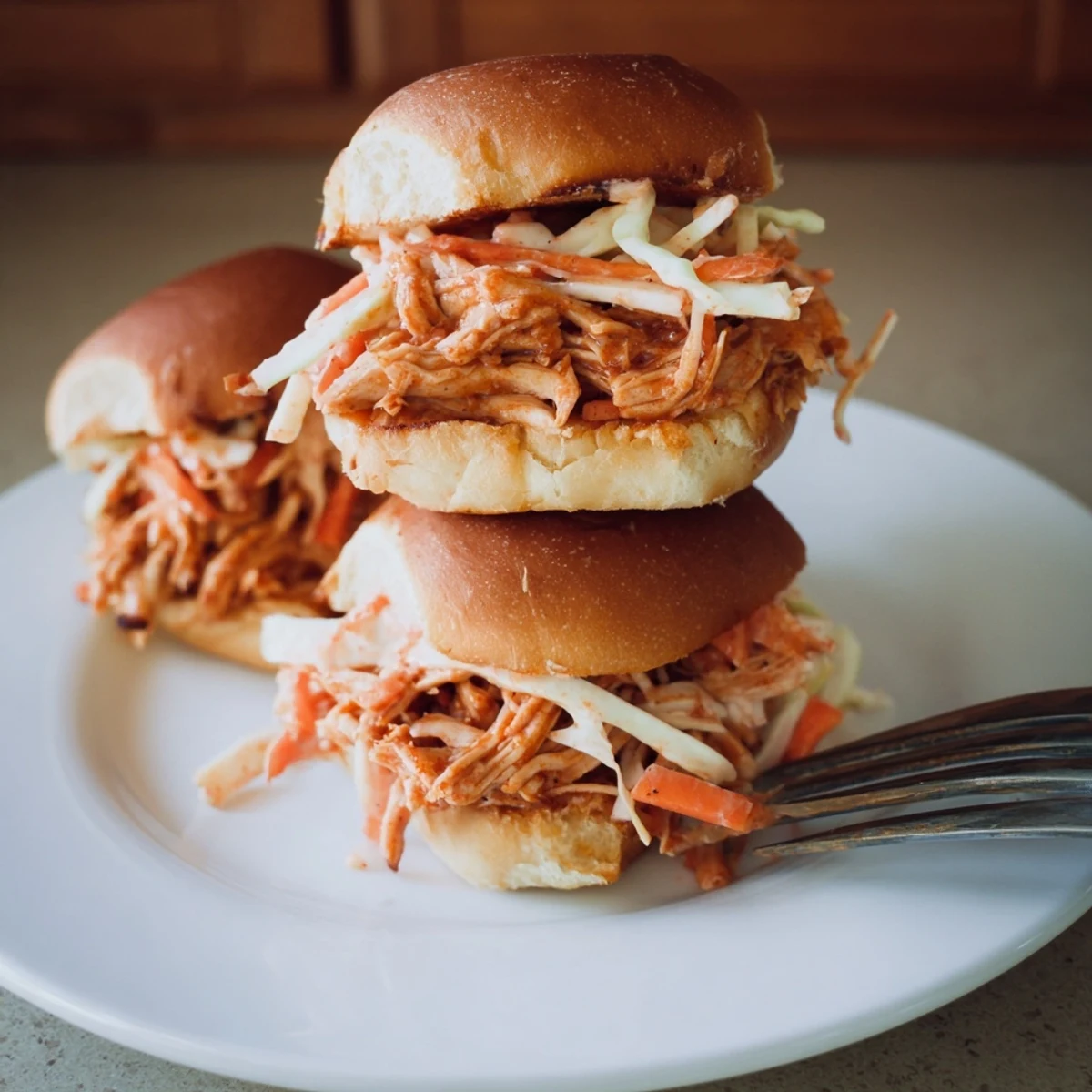 Golden BBQ chicken sliders with crunchy slaw on toasted mini buns, perfect for game day.  