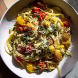 A close-up of the delicious Cozy Fireplace One-Pan Tomato Basil Pasta, glistening with olive oil and cheese.