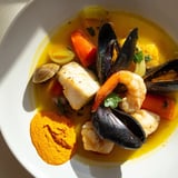 Aromatic bouillabaisse bubbling in a large pot, ready to be ladled and enjoyed with rouille and bread.