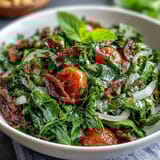 Vibrant dandelion greens salad with lemon vinaigrette and Parmesan, tossed with cherry tomatoes and toasted pine nuts for a zesty Mediterranean starter.
