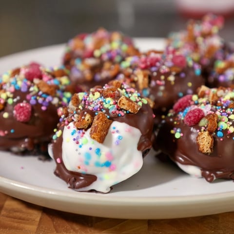 A colorful pile of Chaos Chocolate Cake Bites, swirled with frosting & covered in joyful sprinkles.