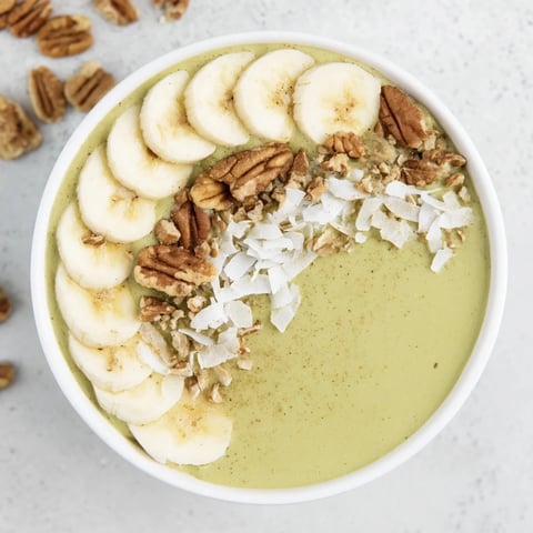 Creamy High-Protein Eggnog Matcha Overnight Oats with banana slices and toasted coconut, ready to eat.