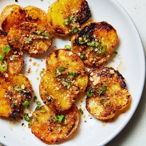Golden, crispy smashed green onion potato bombs, ready to eat, topped with flaky sea salt.