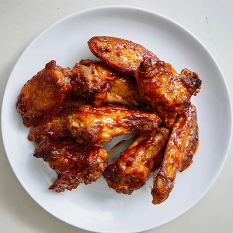 Crispy Baked Sticky Honey BBQ Wings glistening on a baking rack, ready to be devoured at your next party.
