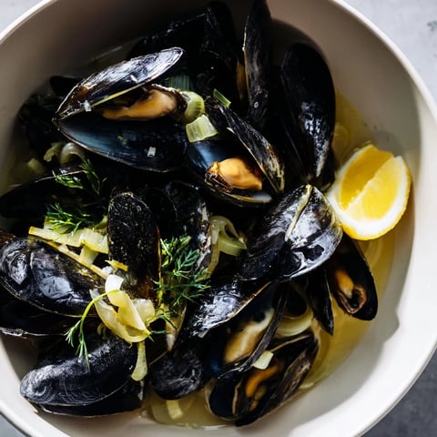 Steaming Belgian Moules Marinière with plump mussels in a fragrant, bubbling white wine broth.