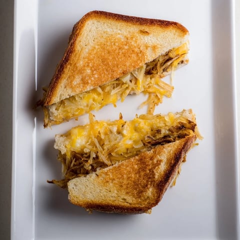 Golden, crispy fried onions and melted cheese peek out of this Crispy Onion Grilled Cheese, served hot on a wooden board.