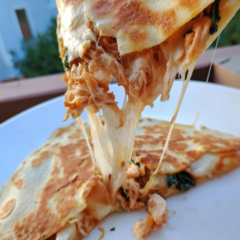 A close-up of golden, crispy Chicken and Spinach Quesadilla wedges, with gooey mozzarella melting between tender spinach and juicy shredded chicken, served on a rustic plate.  