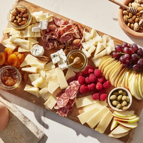 A close-up of a Lace & Pearls Elegant Board, featuring colorful fruits and fine charcuterie.