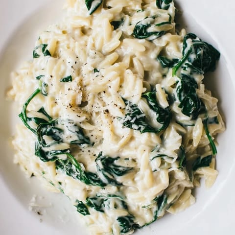 This beautiful image shows a hearty bowl of Creamy Spinach Orzo, perfect for a cozy vegetarian dinner.