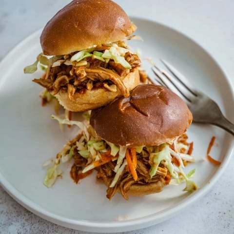 Tender pulled BBQ chicken sliders topped with tangy coleslaw and soft slider buns.  