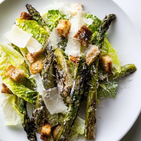Golden homemade croutons and shaved Parmesan rest on a vibrant bed of charred asparagus and romaine in this fresh Roasted Asparagus Caesar Salad.