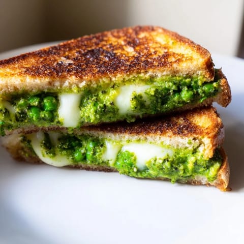 Golden sourdough bread grilled to perfection, holding a bright, savory mix of pea pesto and gooey melted mozzarella cheese.