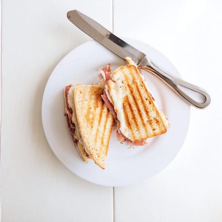 A vibrant plate features the Crispy Prosciutto & Fig Panini, sliced to reveal layers of melted cheese and savory ham.
