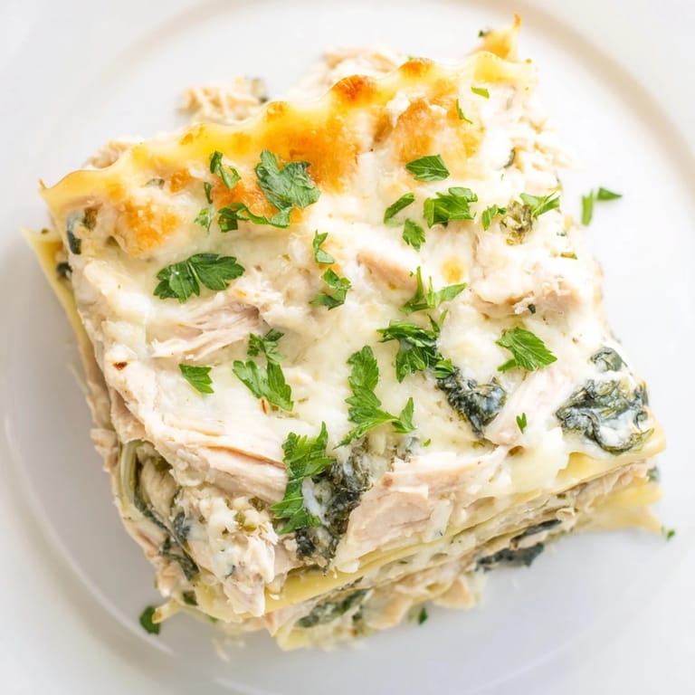Warm slice of creamy Chicken Alfredo Lasagna served on a white plate.