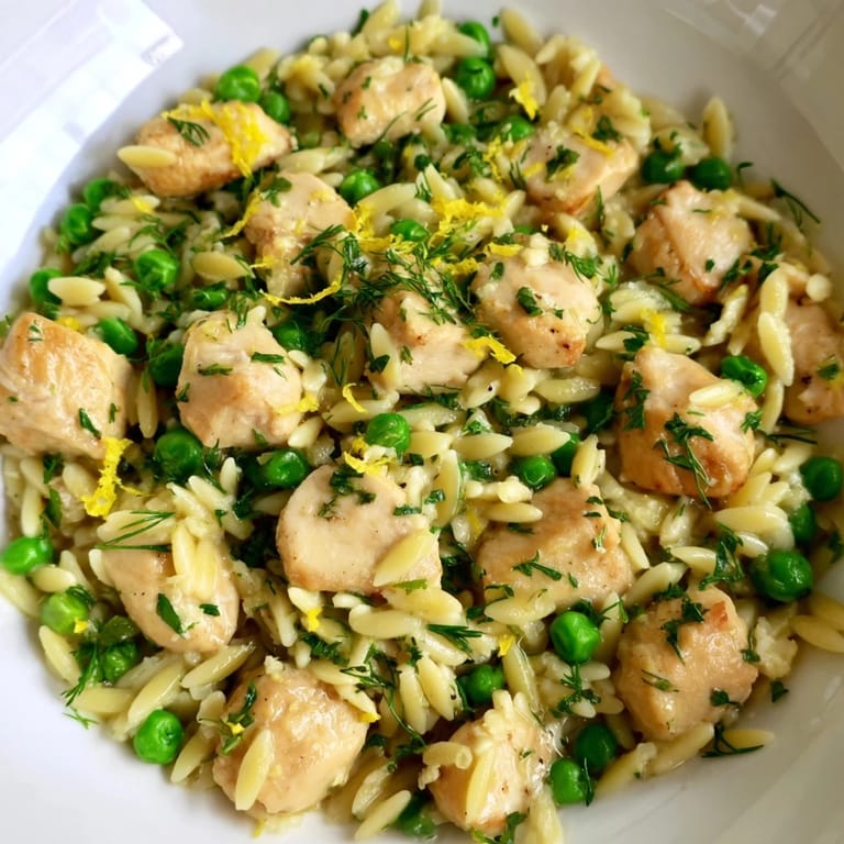 Steaming bowl of Lemon Herb Chicken Orzo Skillet, garnished with fresh herbs and lemon zest, served warm for a family-style meal.