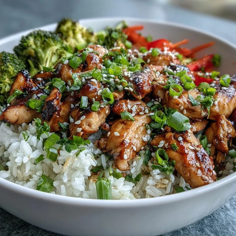A vibrant, wholesome Chicken and Rice Bowl features tender chicken, colorful bell peppers, and carrots, topped with fresh green onions and sesame seeds.