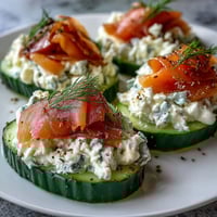 Crisp cucumber rounds topped with creamy cheese and savory smoked salmon for an elegant appetizer.