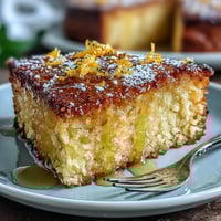 Moist whole orange cake with vibrant citrus aroma, dusted with powdered sugar and served on a rustic wooden table.  